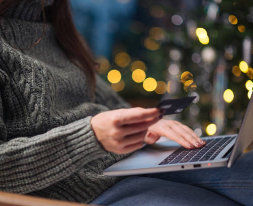 a woman using the computer while holding her credit card on the other hand a woman using the computer while holding her credit card on the other hand