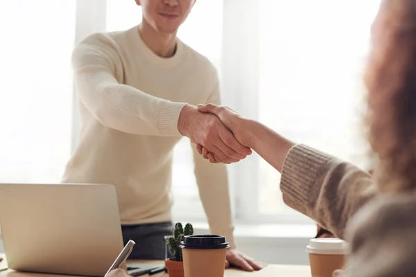 image showing a person in a white shirt shaking hands with another person