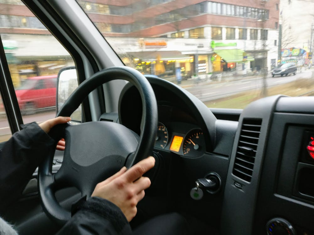 photo showing a hand of a person on the steering wheel as he drives