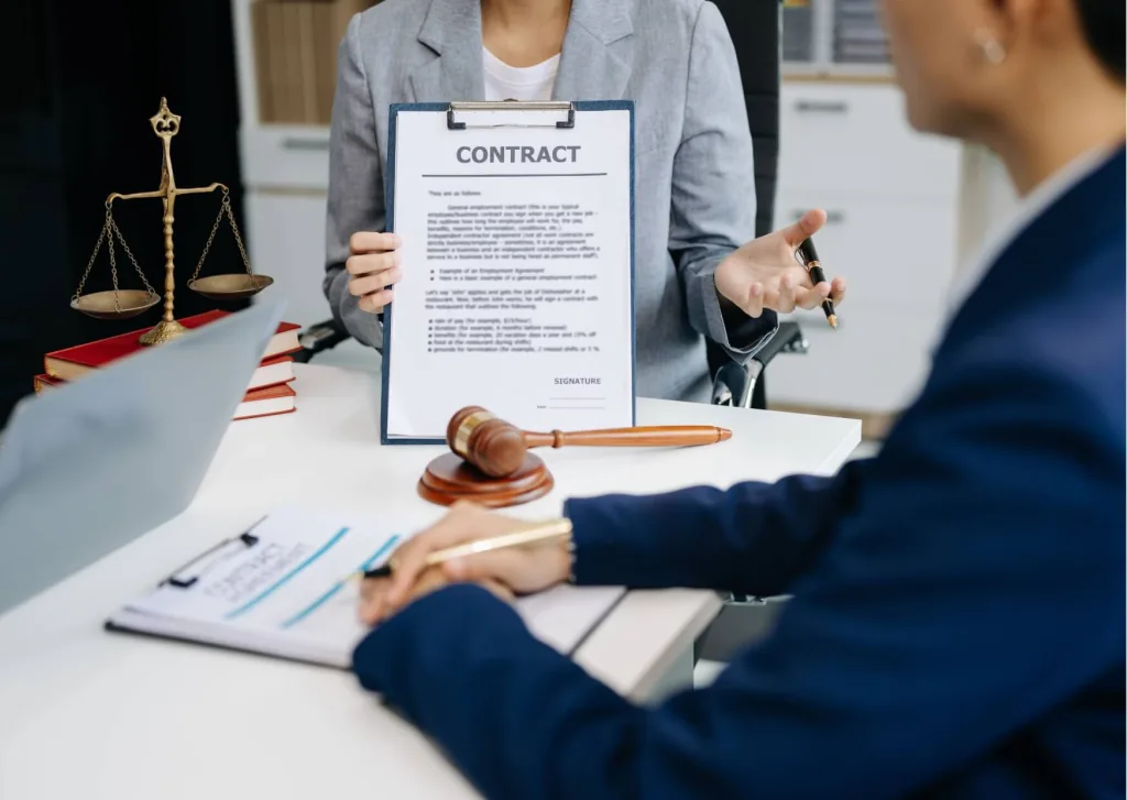 Attorney presenting an employment contract across a desk with scales of justice and a gavel