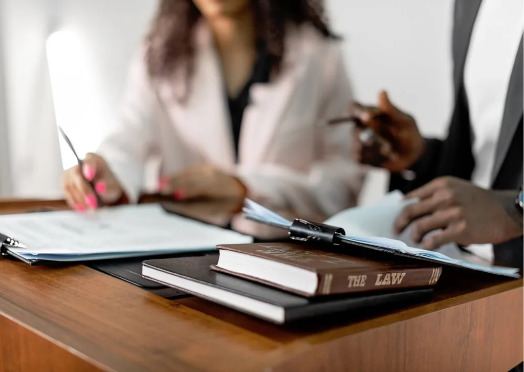 Worker and attorney reviewing wage records at a desk beside a law book